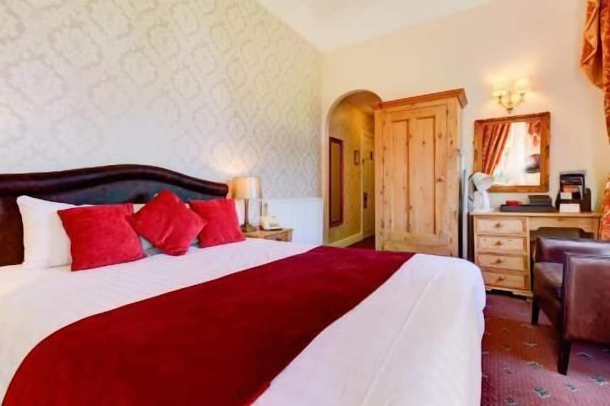 A hotel room with a bed, a desk, a wardrobe, and a mirror.