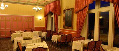 A dining area with round tables, chairs, and a chandelier.