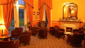 Een hotel lobby met een open haard, meerdere zithoeken en een grote spiegel.