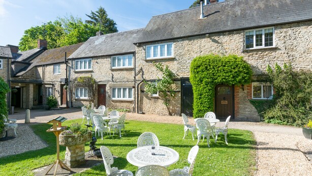 A stone building with a courtyard. There are white chairs and tables arranged in the courtyard. - The Jersey Arms , Sure Coll. by Best W (Bicester)