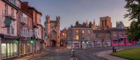 A street view with a historic building, shops, and a bus stop.