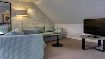 A modern living room with a sofa, a small table, a lamp, and a TV.