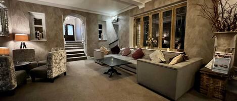 Amplia sala de estar con candelabro, una escalera y vistas al exterior.
