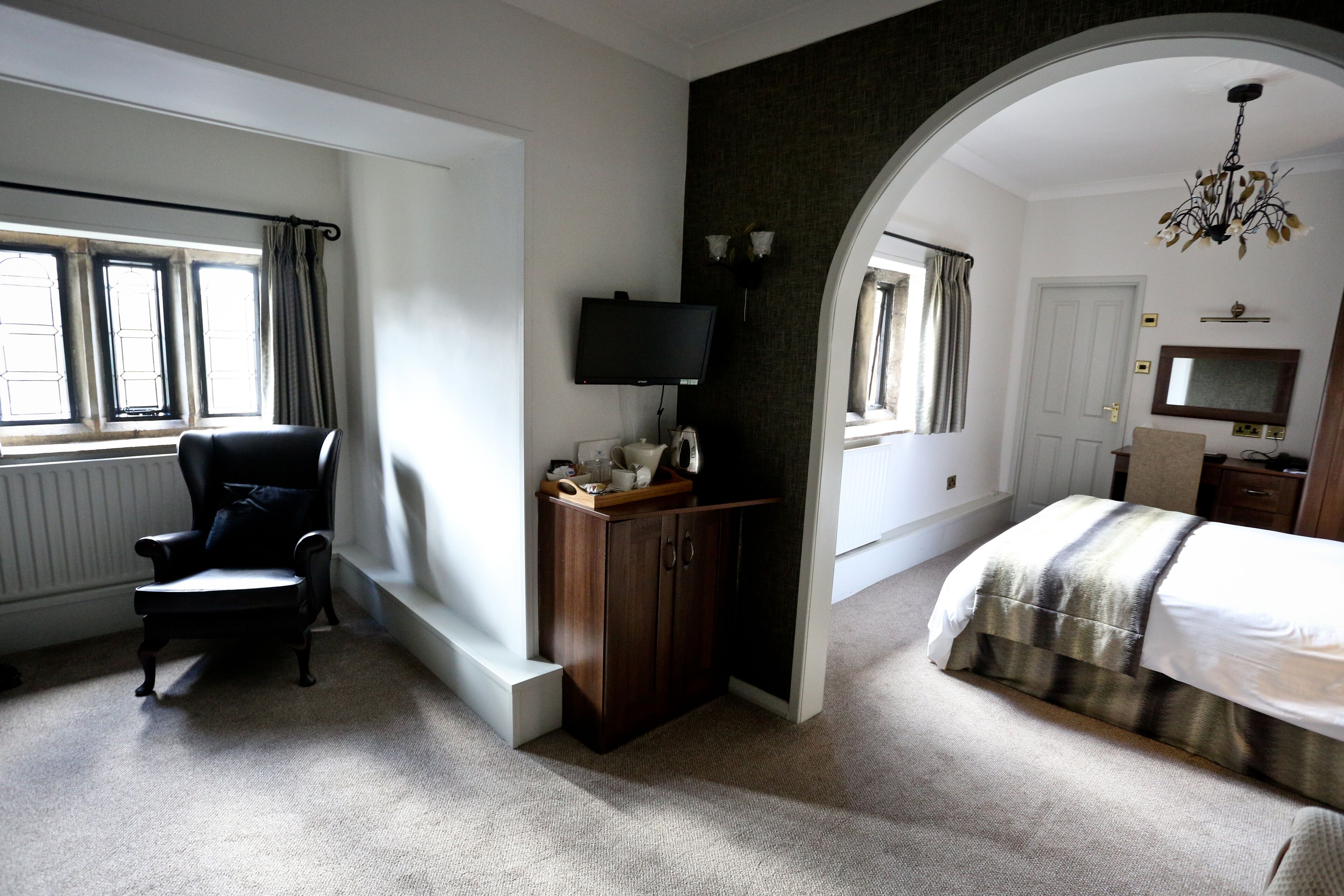 A bedroom with a bed, a chair, a TV, and a wardrobe.