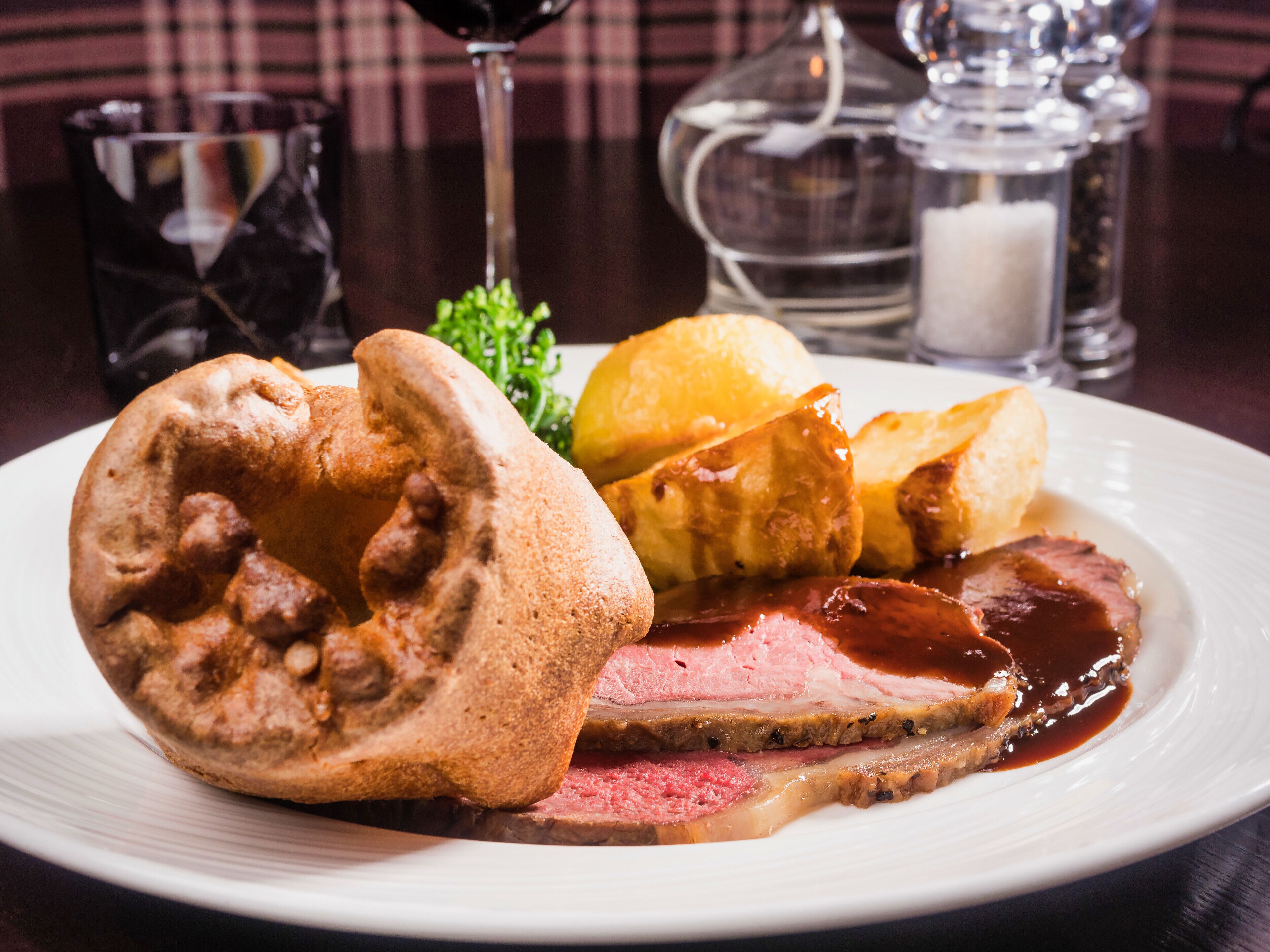 A plate of food with roast beef, Yorkshire pudding, and Yorkshire pudding with gravy.