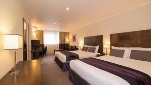 A hotel room with two beds, a desk, a TV, and a lamp. - Regency Park Hotel (Thatcham)