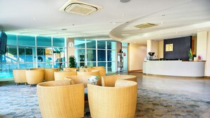 A lobby with wicker furniture, a reception desk, and large windows. - Regency Park Hotel (Thatcham)