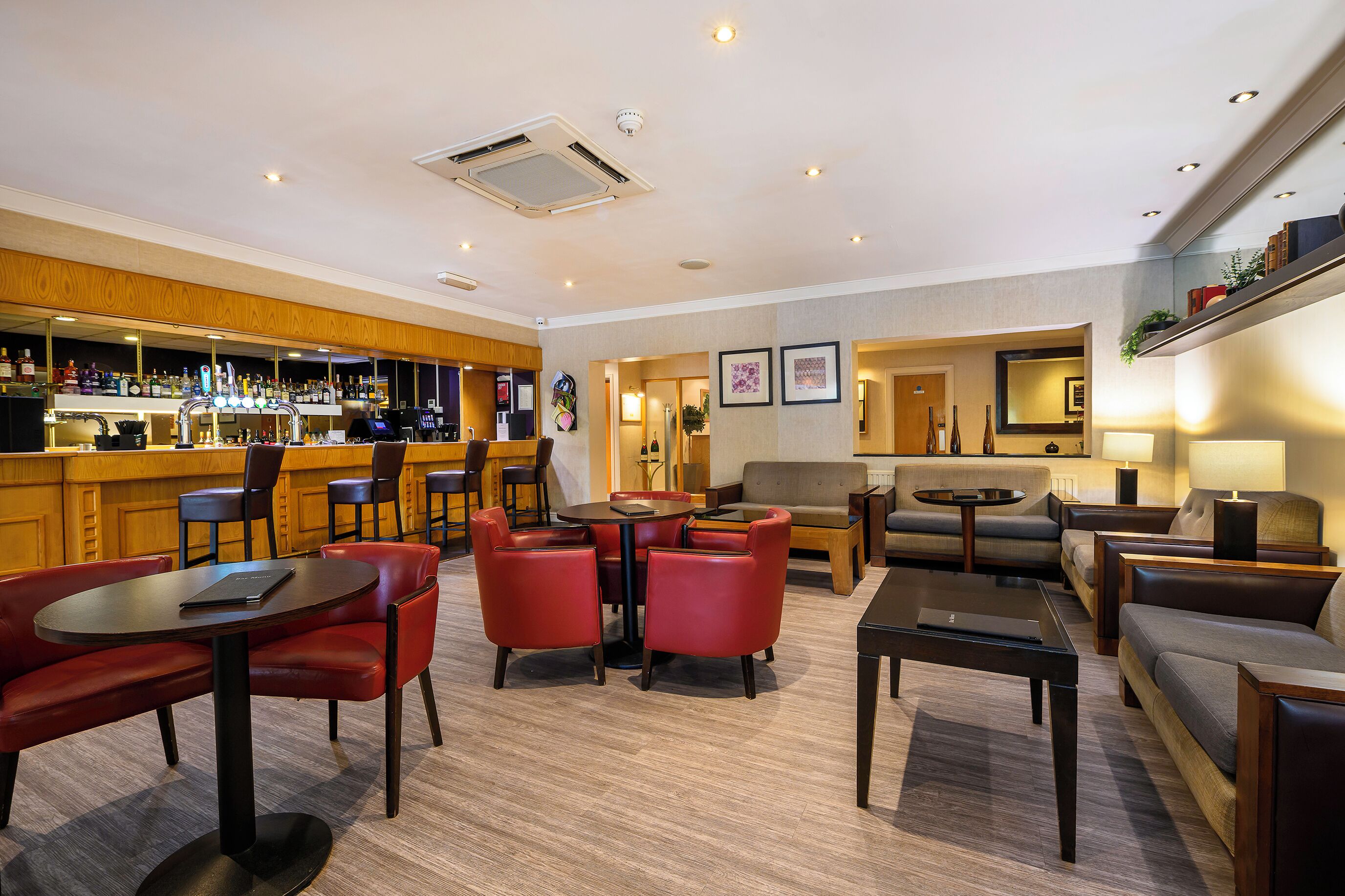 A hotel lobby with a bar area, seating arrangements, and a reception desk.