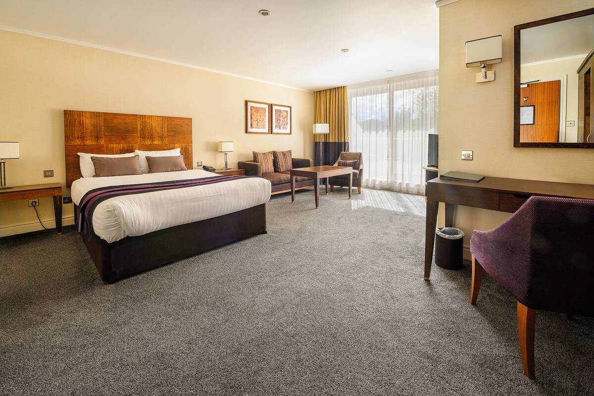 Ein Hotelzimmer mit einem großen Bett, einem Schreibtisch, einem Stuhl und einem Spiegel.
