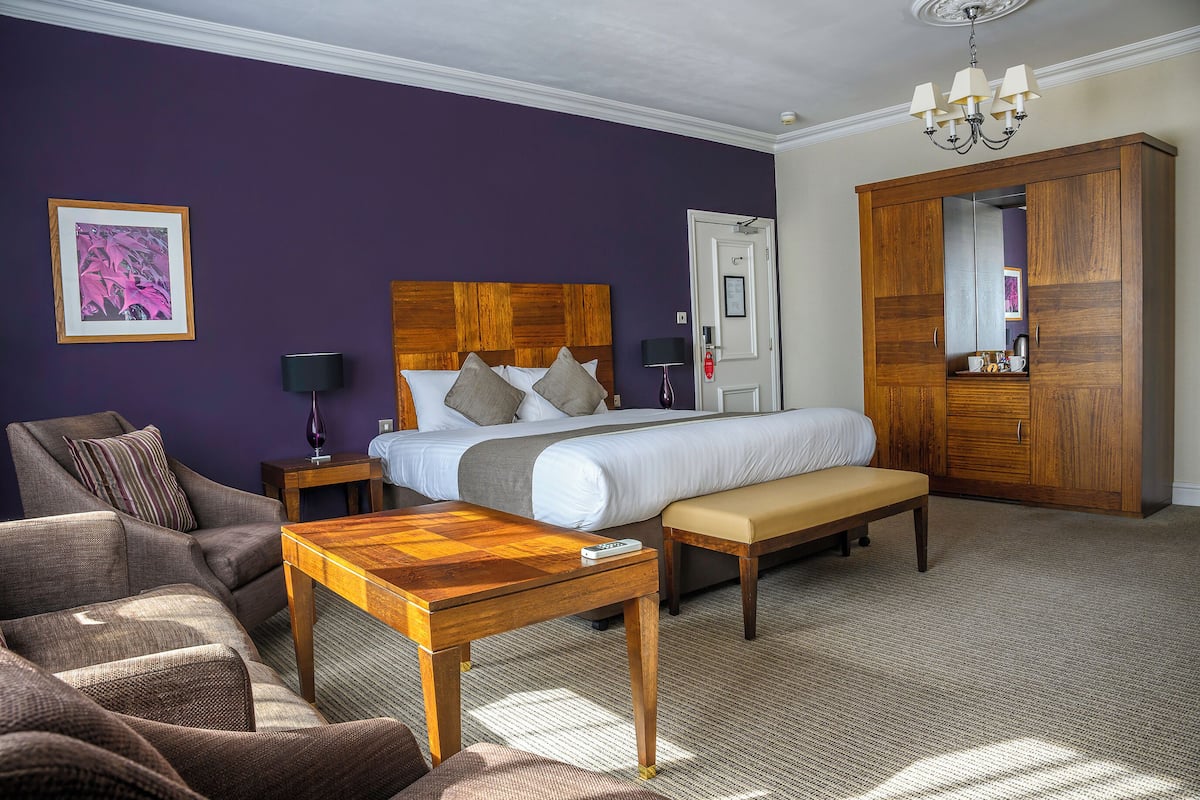 Ein Schlafzimmer mit Bett, einem Holzschrank, einer Bank, einem Tisch und einem Stuhl.