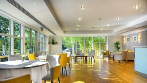 A spacious dining area with large windows, wooden flooring, and modern furniture. - Regency Park Hotel (Thatcham)