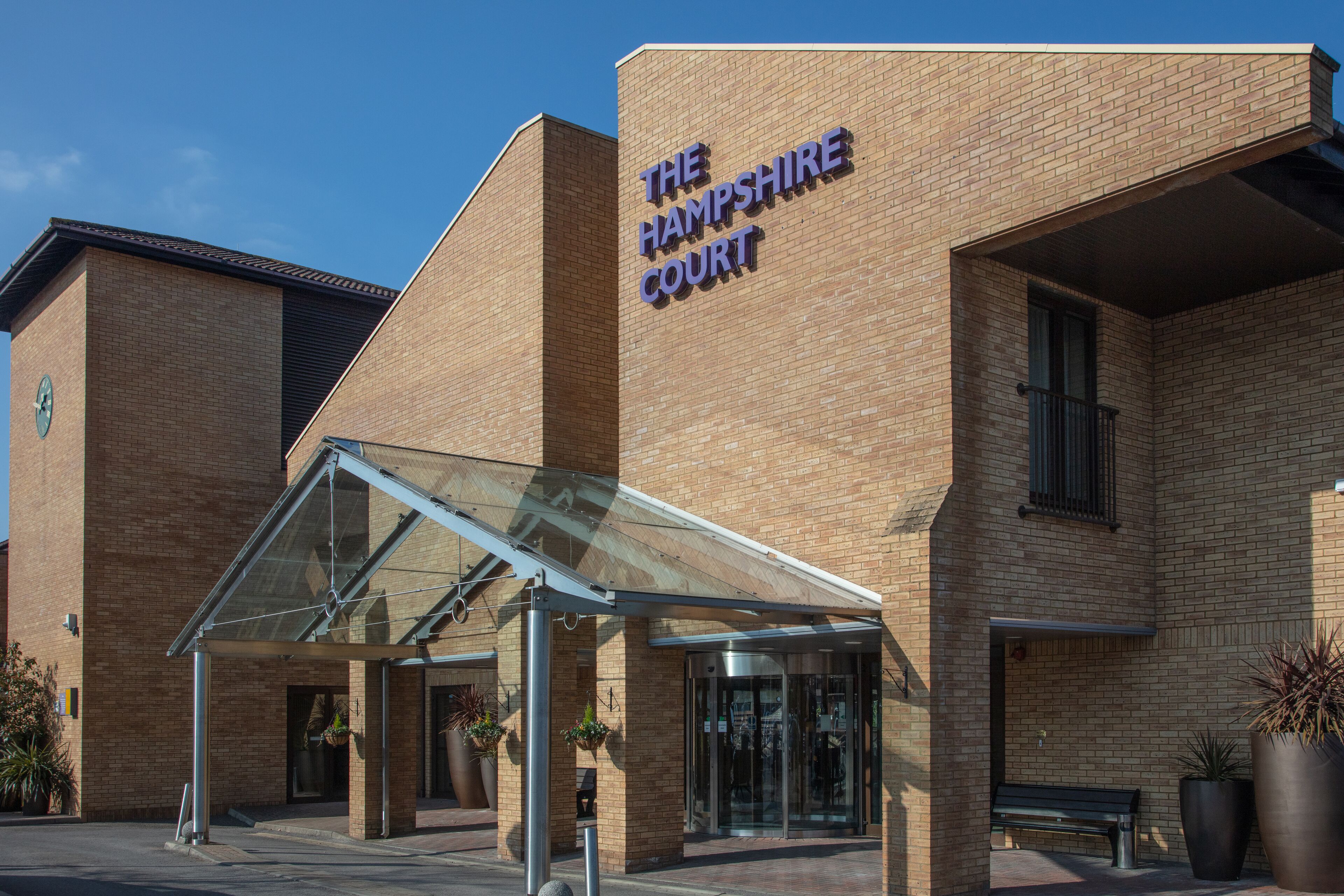 A modern brick building with a glass entrance and a sign reading "The Hampshire Court".
