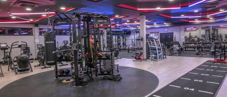 Une salle de sport équipée de divers appareils d’exercice, d’un espace dédié à la musculation et d’une piste d’athlétisme.