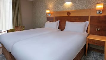 A double bed with two pillows, a wooden headboard, bedside tables, and a chair.