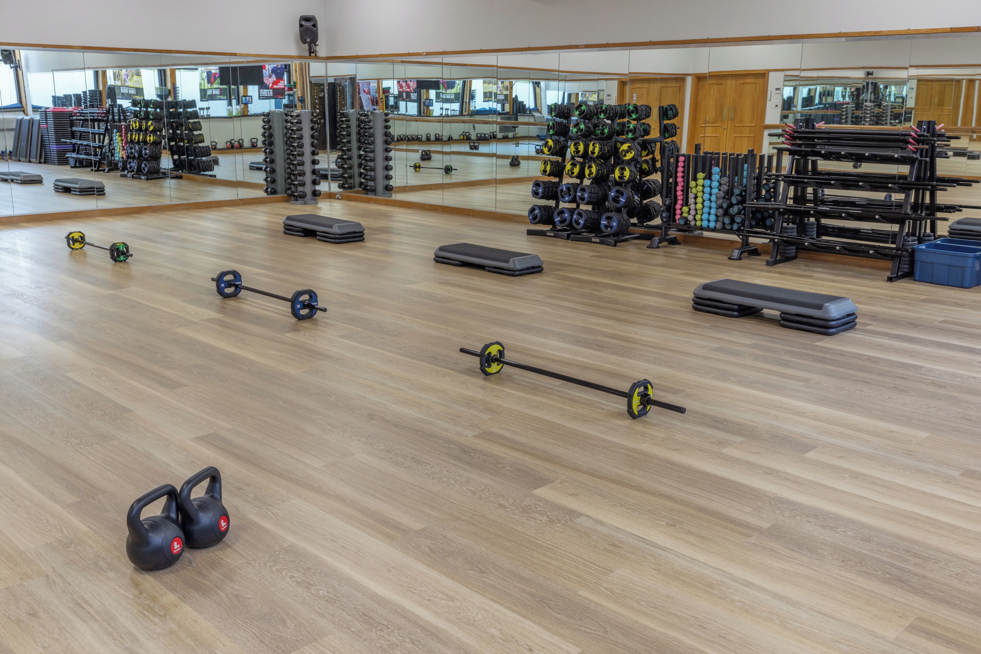A gym with various exercise equipment, including kettlebells, barbells, and weight plates.