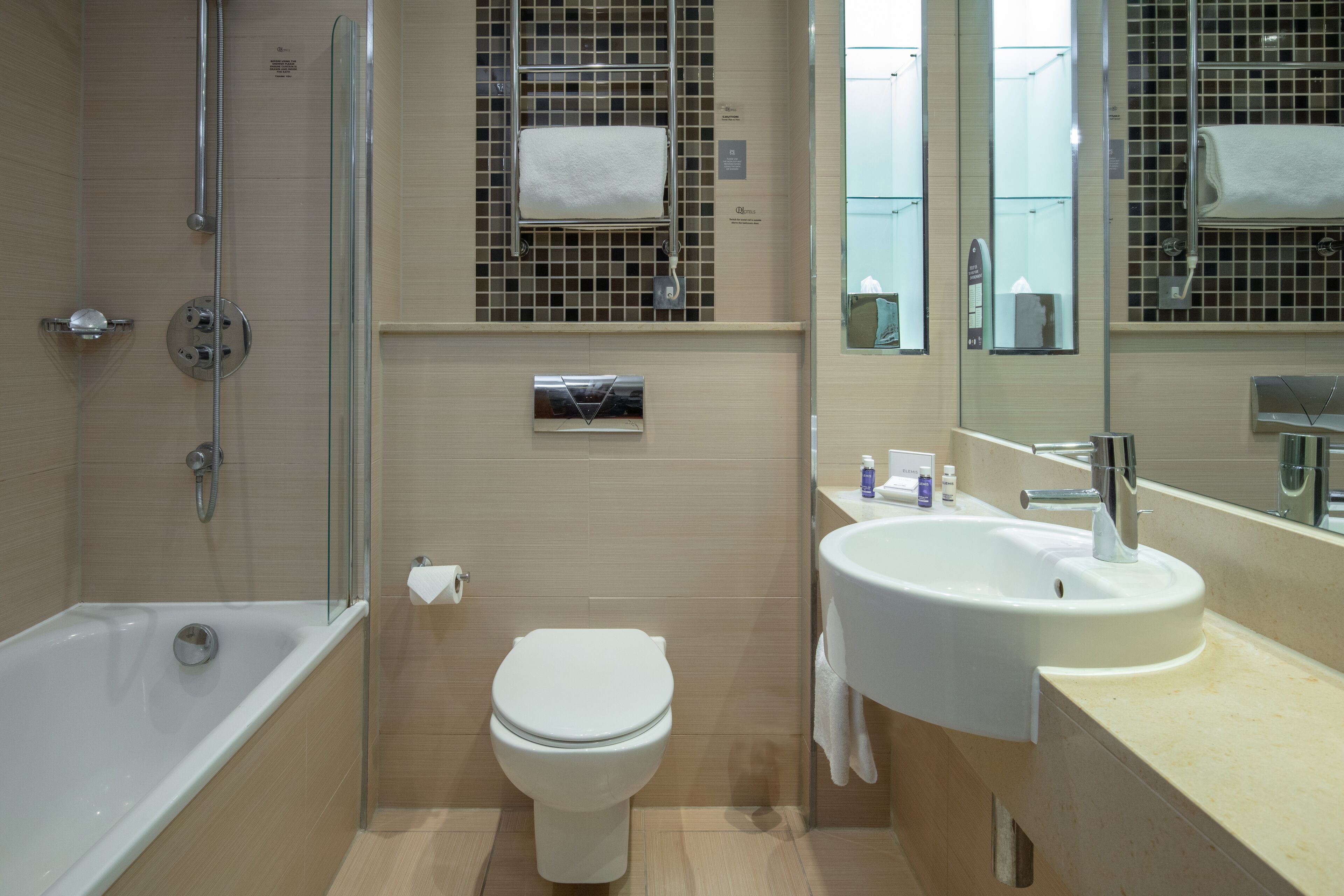 Un baño moderno con ducha envuelta en vidrio, inodoro blanco y lavamanos con espejo superior.