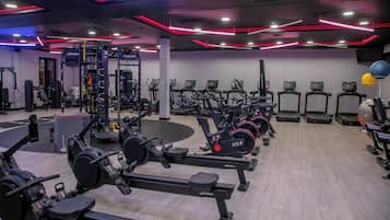 A gym with various exercise equipment including treadmills, elliptical machines, and weight machines.