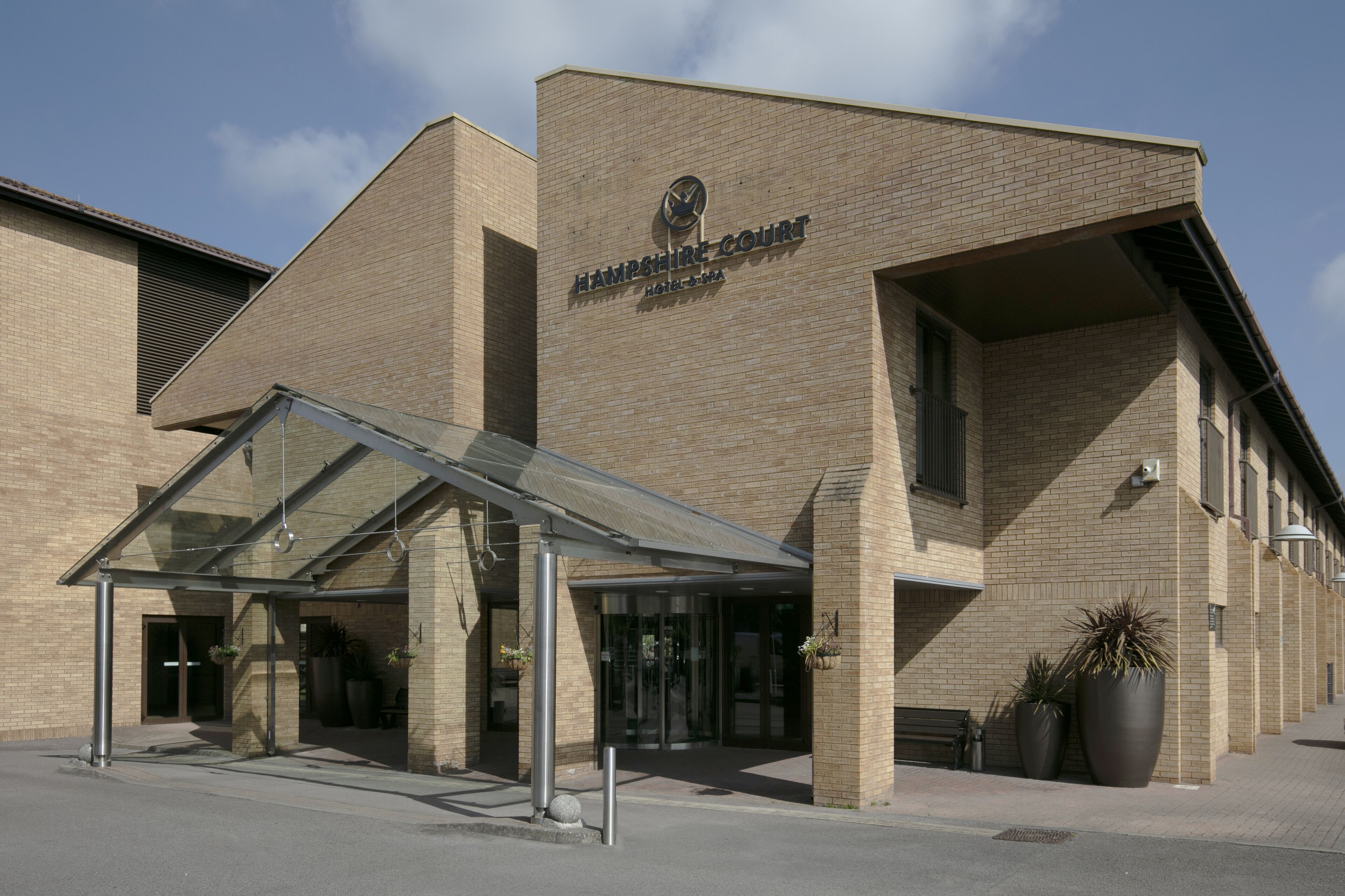 A modern brick building with a glass entrance canopy, labeled "Hampshire Court Hotel & Spa."