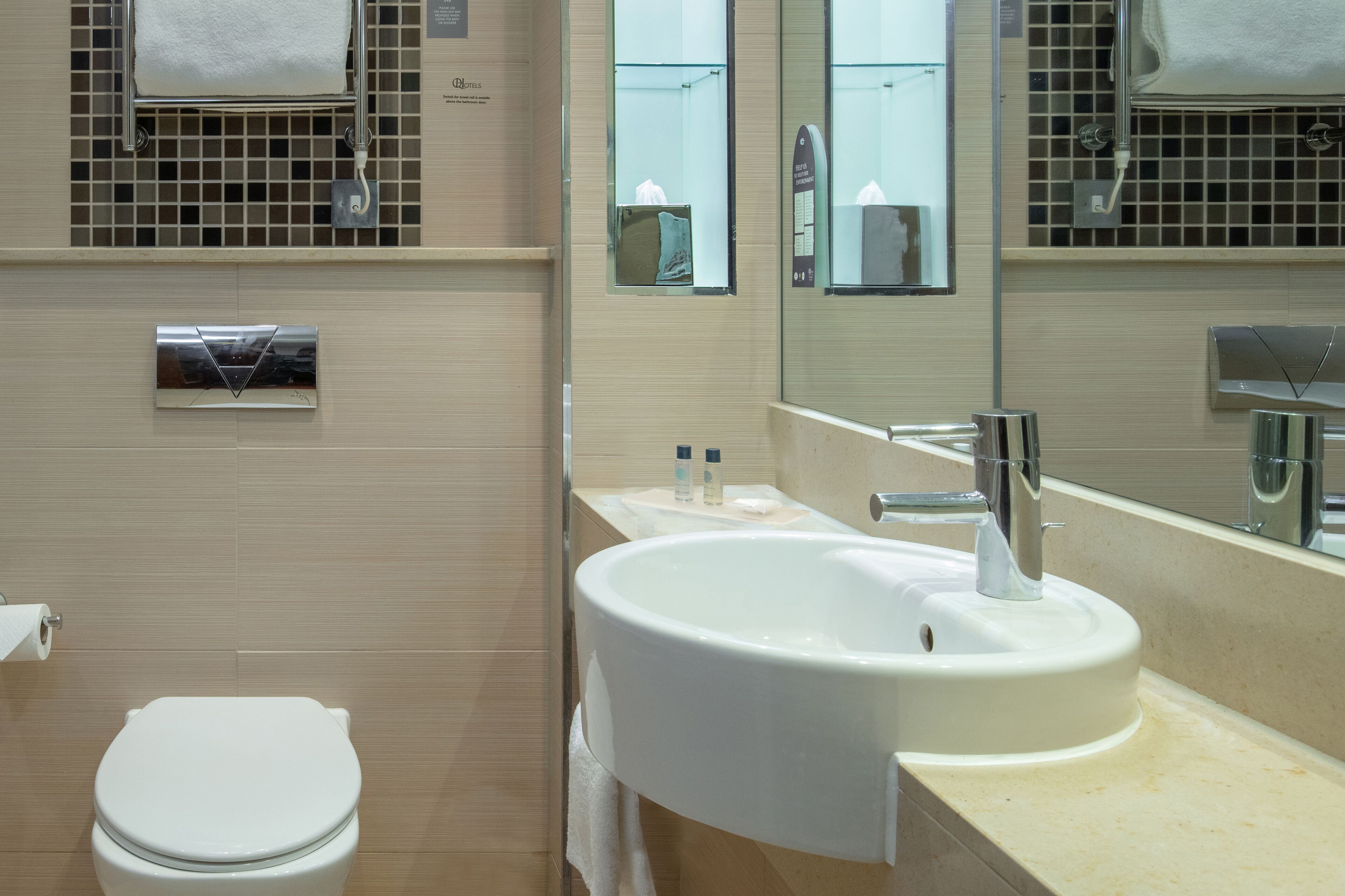 Un baño moderno con inodoro, lavamanos y espejo.