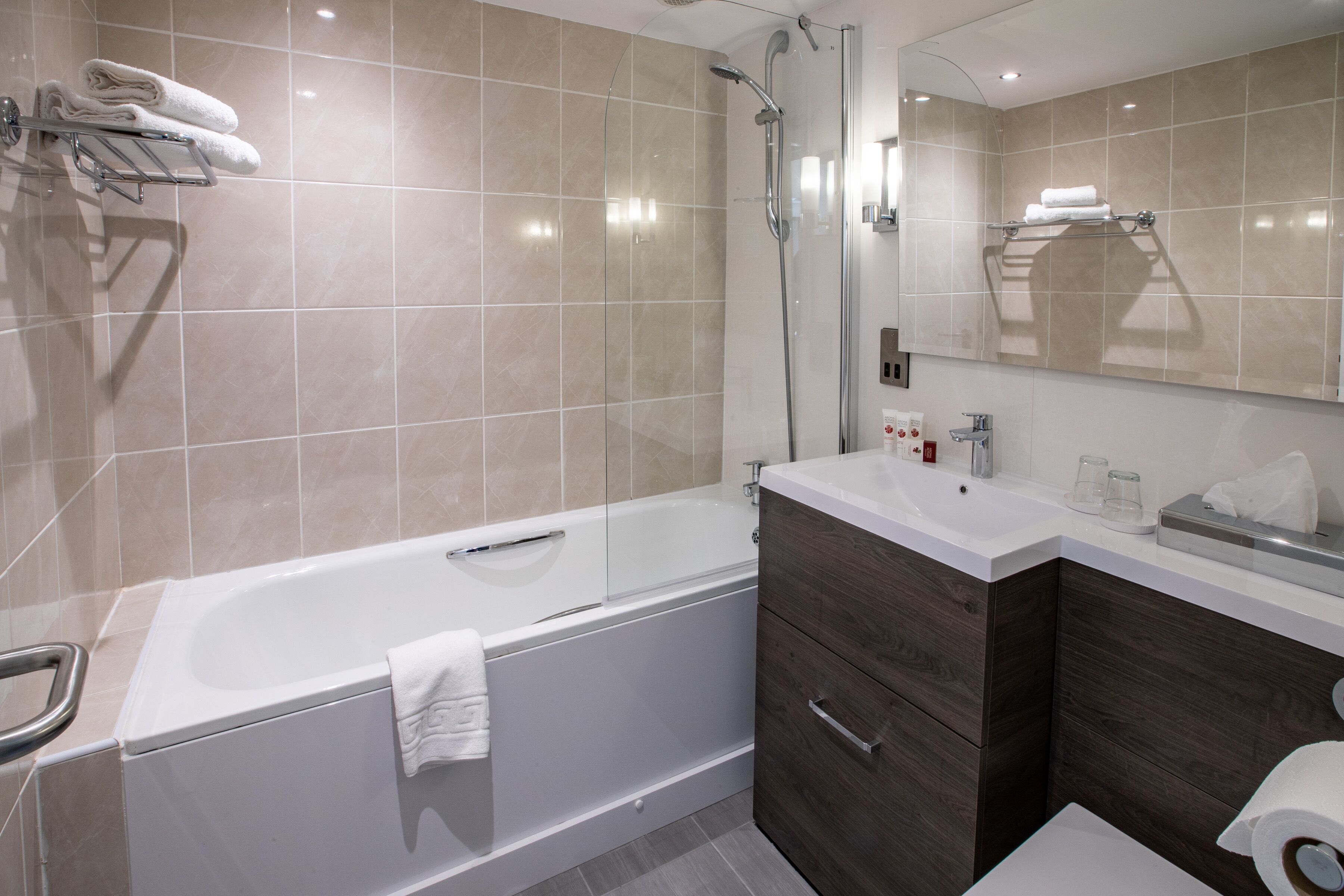 A modern bathroom with a bathtub, a glass shower enclosure, a vanity with a mirror, and a towel rack.