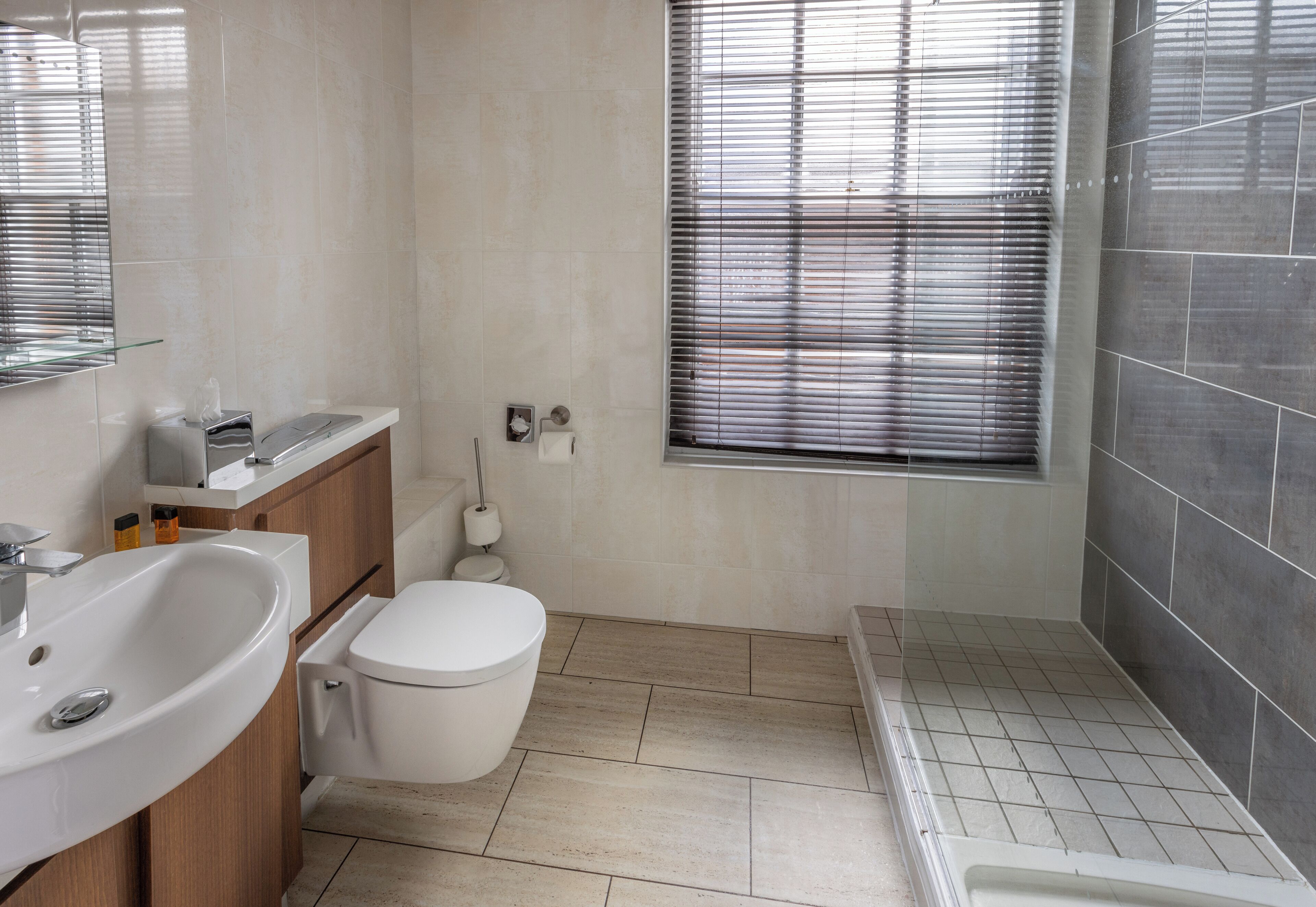 A modern bathroom with a white sink, toilet, and shower area.