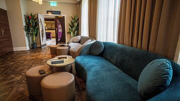 A hotel lobby with a blue sofa, two ottomans, a small table, and a reception desk.