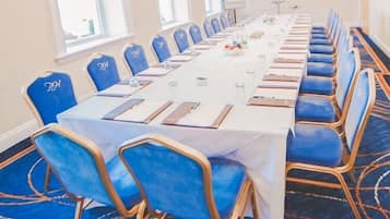 A conference room with a long table, blue chairs, and a carpeted floor.