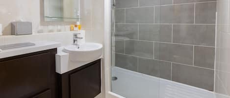A modern bathroom with a shower, sink, and toilet.