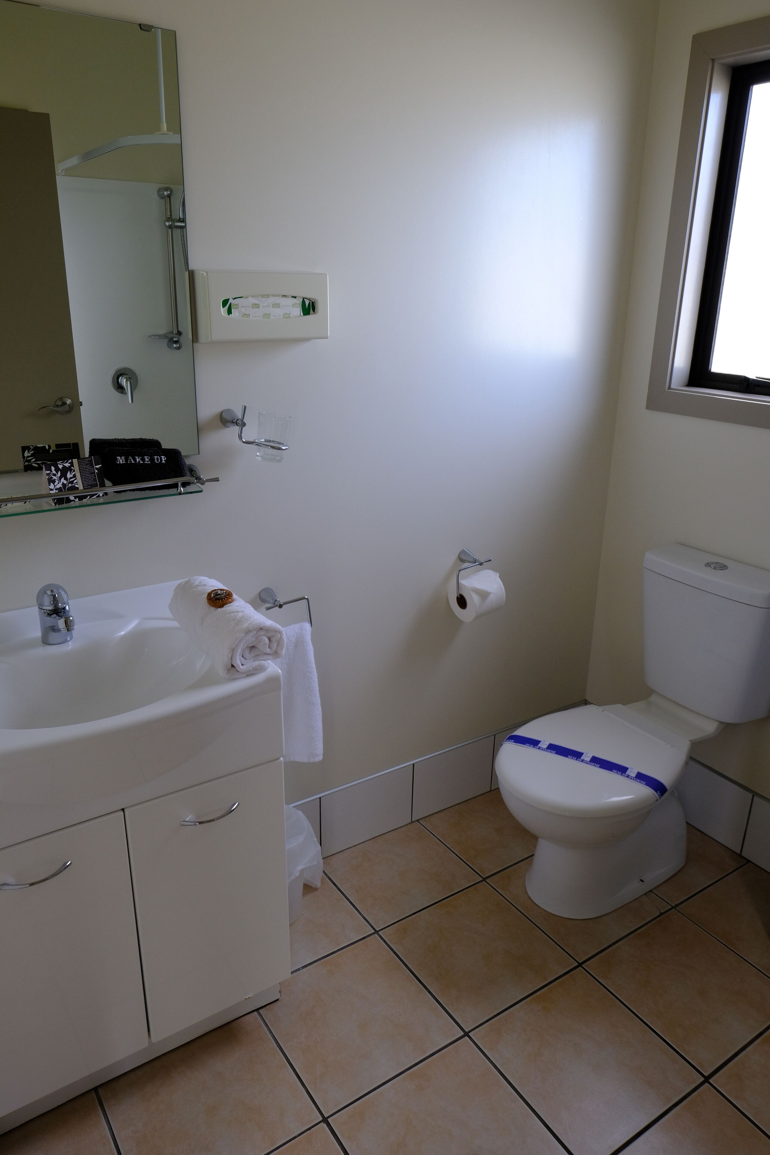 A bathroom with a white sink, mirror, and toilet.