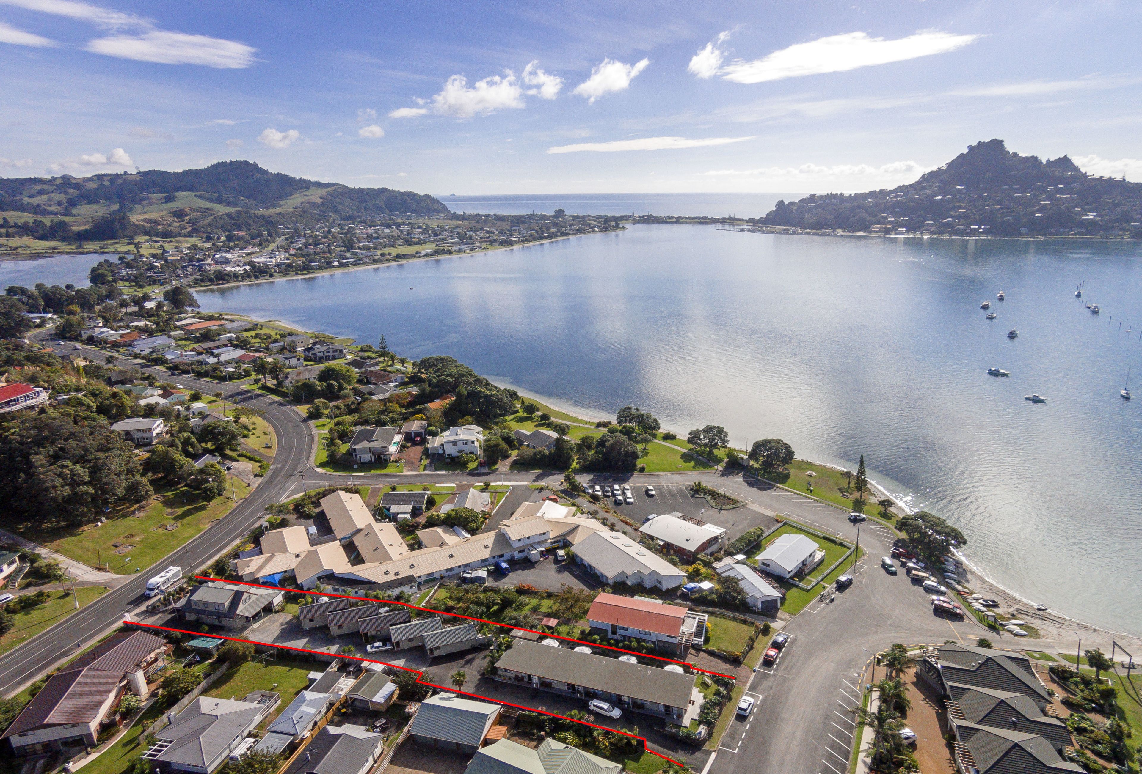 A coastal town with a marina, houses, and a road leading to the water.