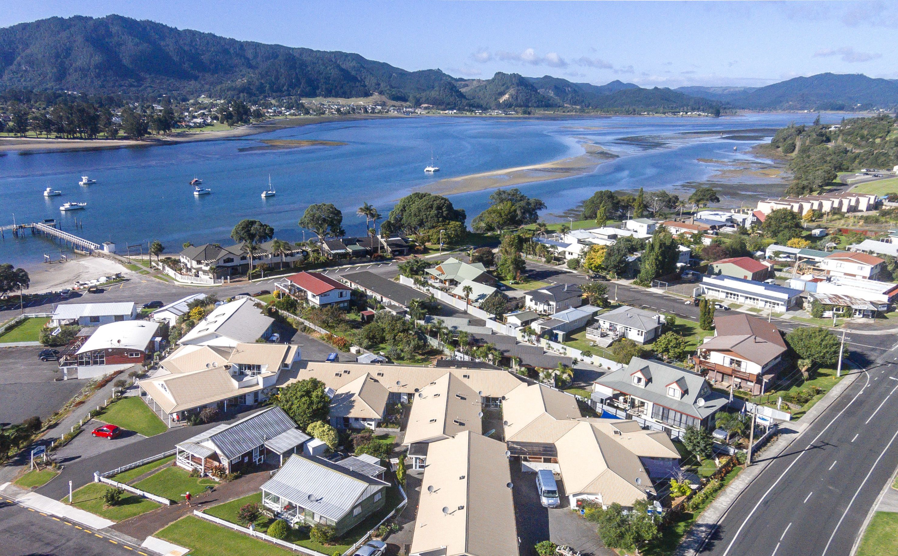 An aerial view of a coastal residential area with houses, a marina, and a road.