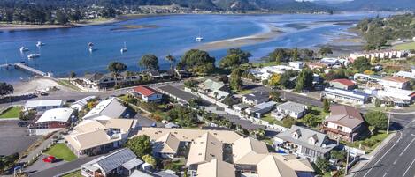An aerial view of a coastal residential area with houses, a marina, and a road.
