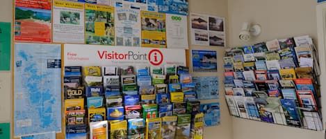 A wall filled with travel brochures and maps, including sections for VisitorPoint and various tours.