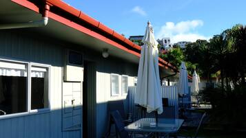 Um hotel com telhado vermelho, área de estar ao ar livre com guarda-sóis e um deck de madeira.