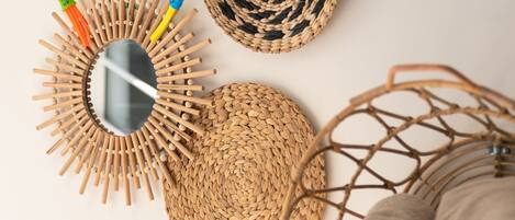A woven basket, a mirror with wooden sticks, and rolled fabric on a white surface.