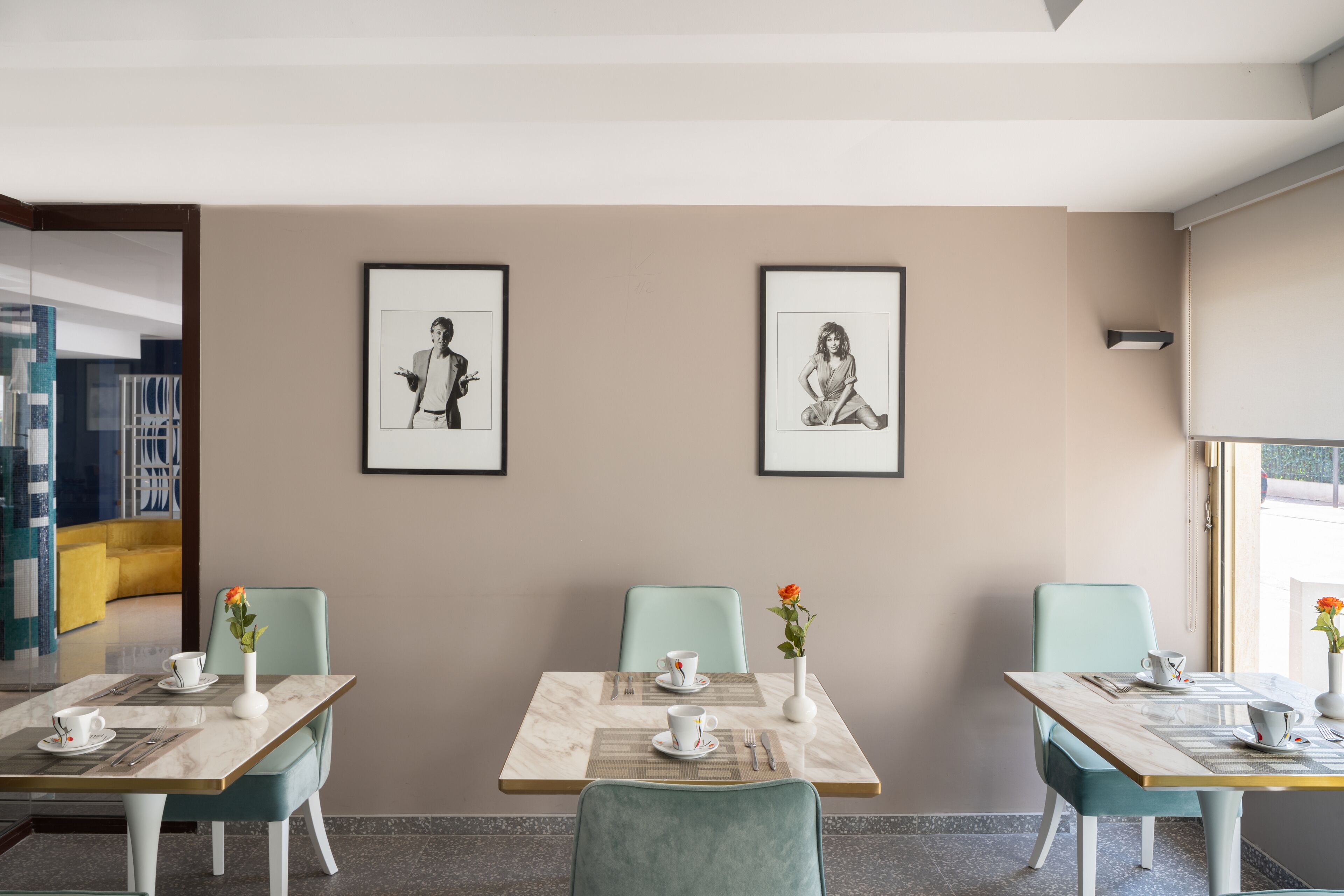A modern dining area with two tables, each with a vase of flowers, a cup, and a saucer.
