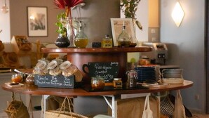 Un café con mostrador de madera que exhibe pasteles y bebidas, un reloj y una pizarra con el menú.