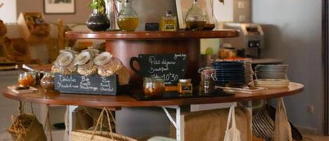 A café with a wooden counter displaying pastries and drinks, a clock, and a chalkboard menu.