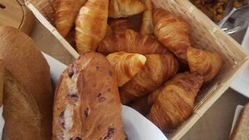 Diverse gebakjes, waaronder croissants en brood, uitgestald op een tafel.