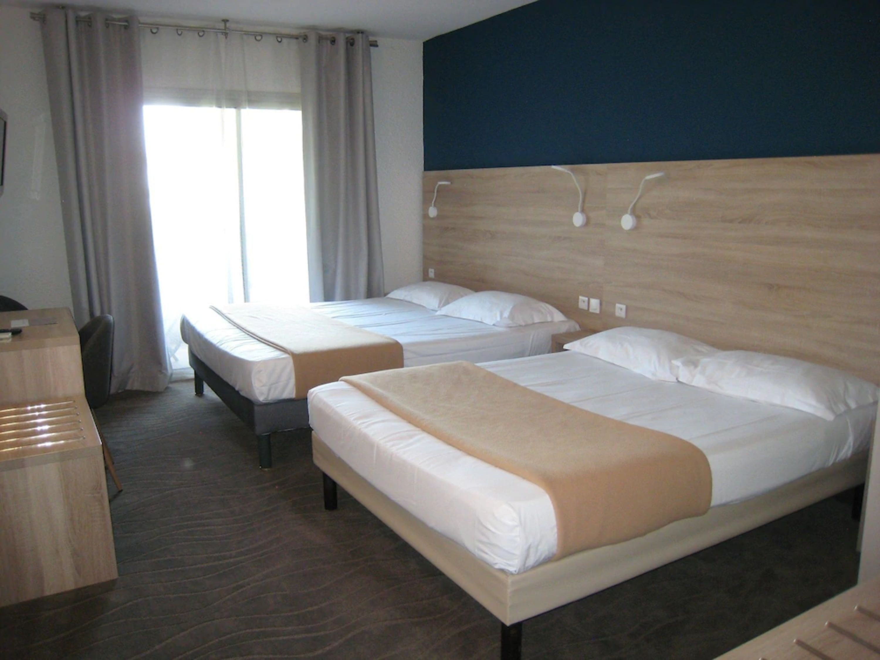 A hotel room with two beds, a desk, and a chair.
