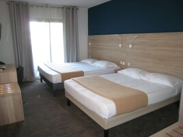 A hotel room with two beds, a desk, and a chair.