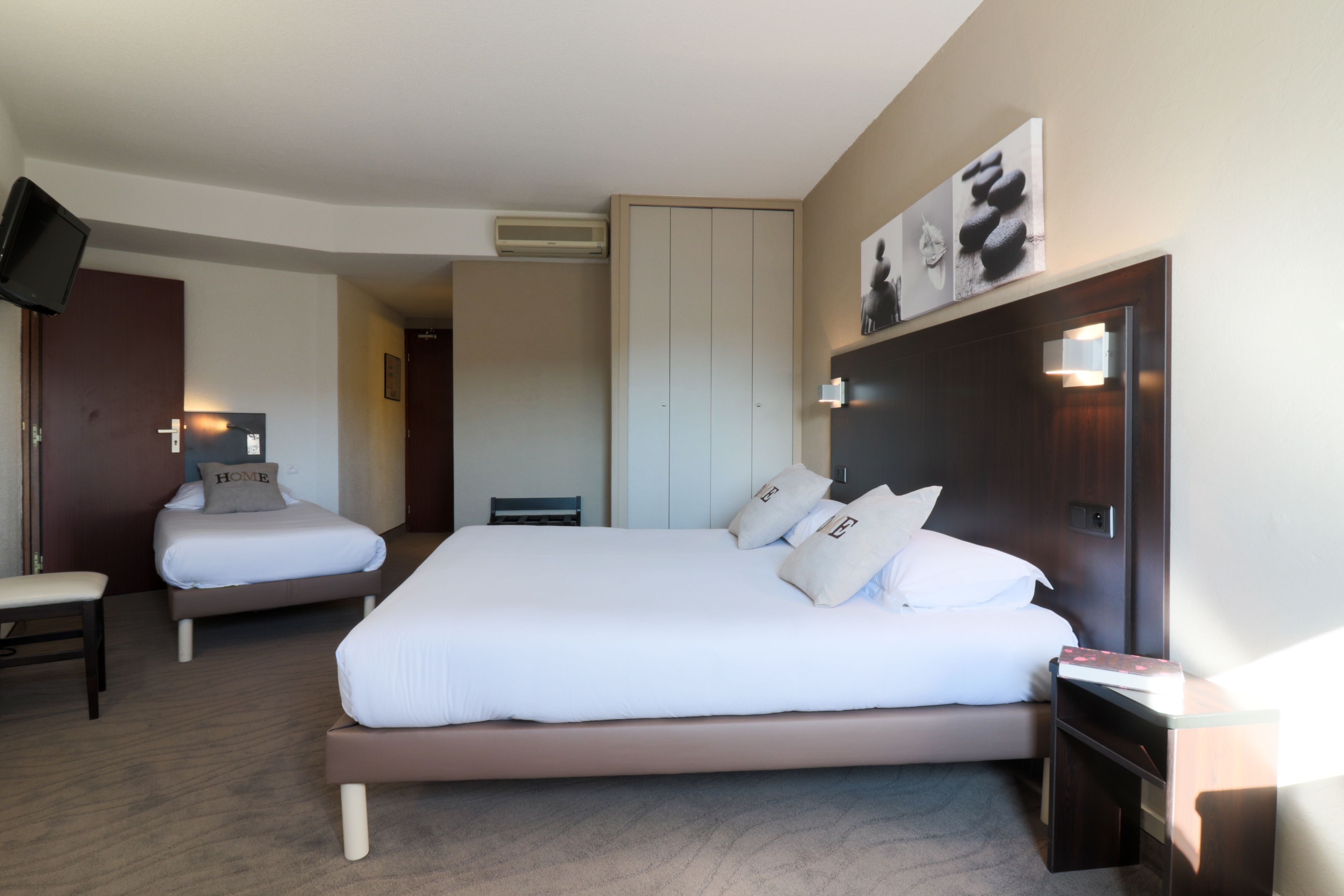 A hotel room with two beds, a TV, a desk, and a wall-mounted artwork.