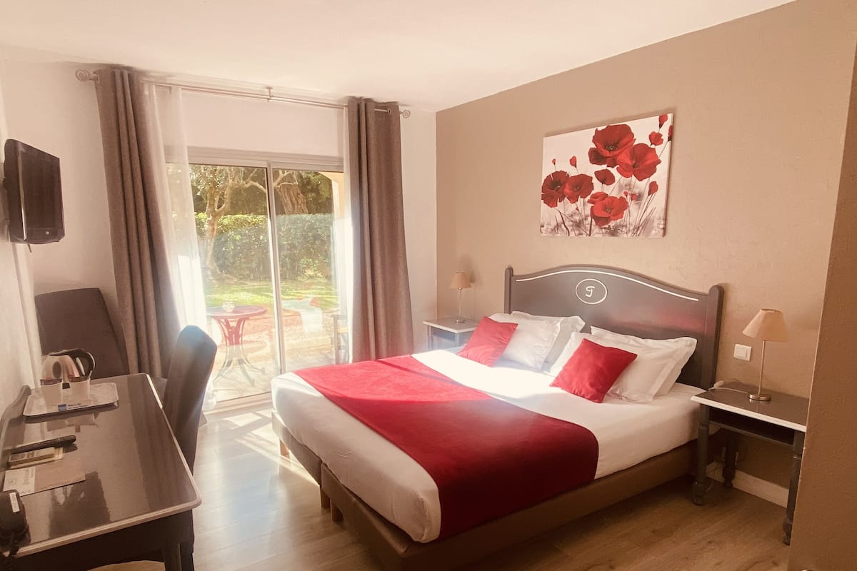 Une chambre d’hôtel équipée d’un lit, d’un bureau, d’une chaise, d’une table et offrant une vue sur l’extérieur.
