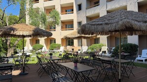 An outdoor patio area with thatched umbrellas, tables, and chairs. - Le Floréal (Vence)