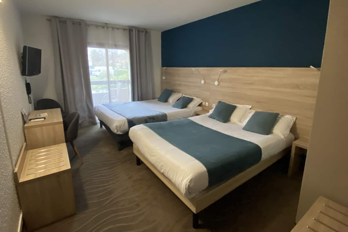 Une chambre d’hôtel avec deux lits, un bureau et une chaise.