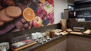 A breakfast buffet with various food items and a large fruit and nut mural on the wall. - Le Floréal (Vence)