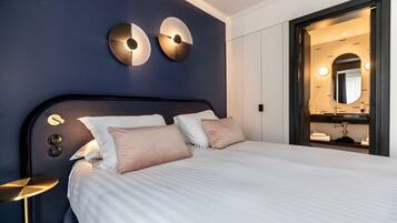 A neatly made bed with a headboard, a bedside table, and wall-mounted lighting fixtures.