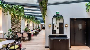A modern hotel lobby with a long reception desk, multiple seating areas, and hanging plants. - Best Western Plus Crystal, Hotel & Spa (Nancy)