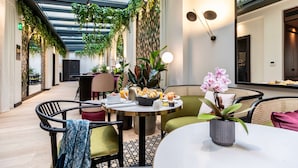 A modern indoor dining area with a glass ceiling, green plants, and a table set with breakfast items. - Best Western Plus Crystal, Hotel & Spa (Nancy)