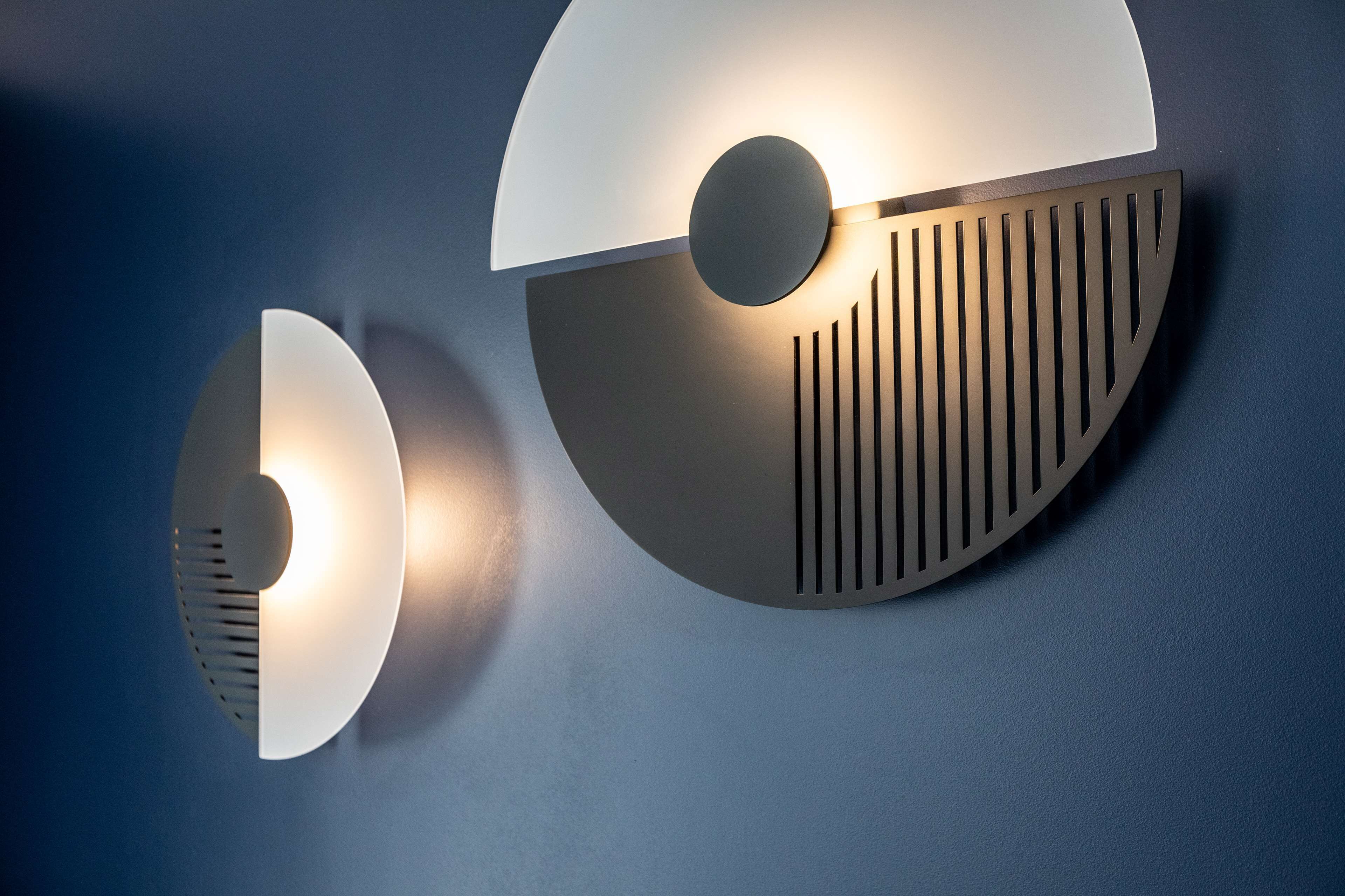 A wall-mounted light fixture with a circular design and a central illuminated bulb.